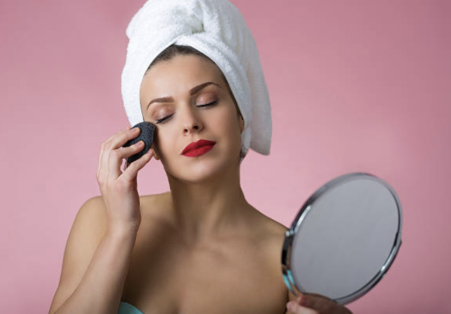 Women cleansing her face with bamboo charcoal konjac sponge
